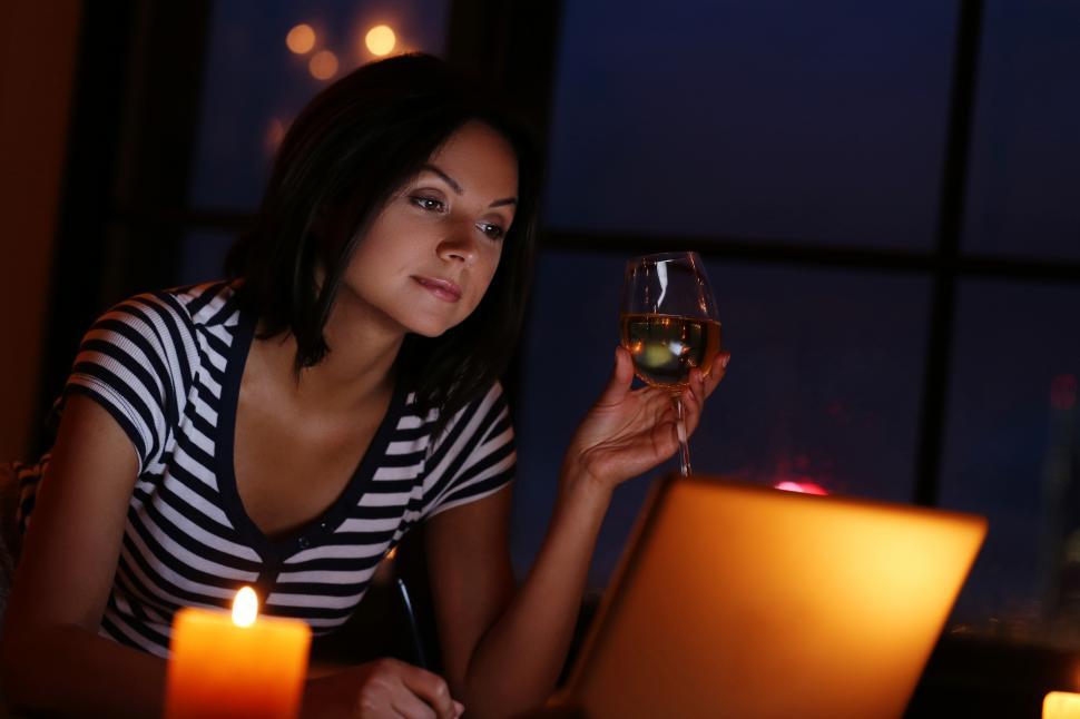 Free Image of Woman with a glass fo wine in candle light setting 