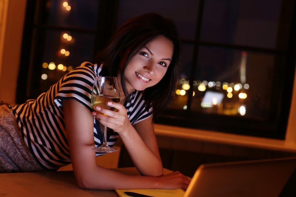 Free Image of Woman with a glass of wine in low light 