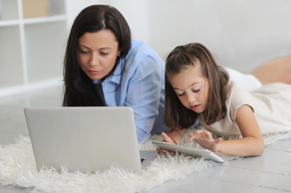 Free Image of Mother and daughter laying on the floor, working on computerts 