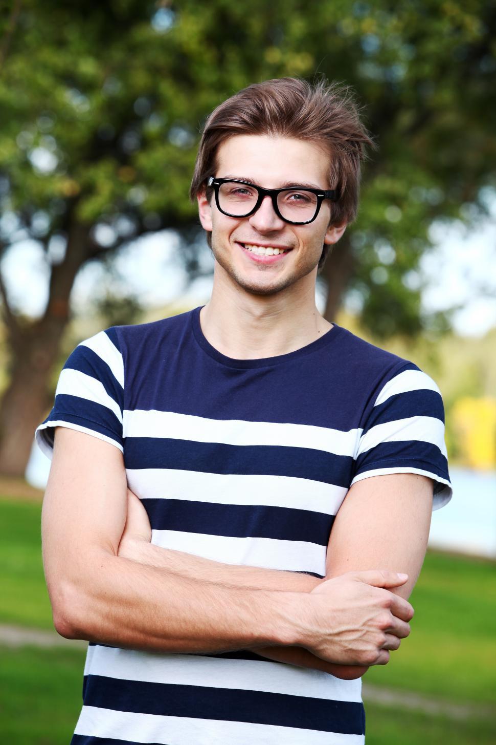 Free Image of Guy standing in a park, arms crossed 