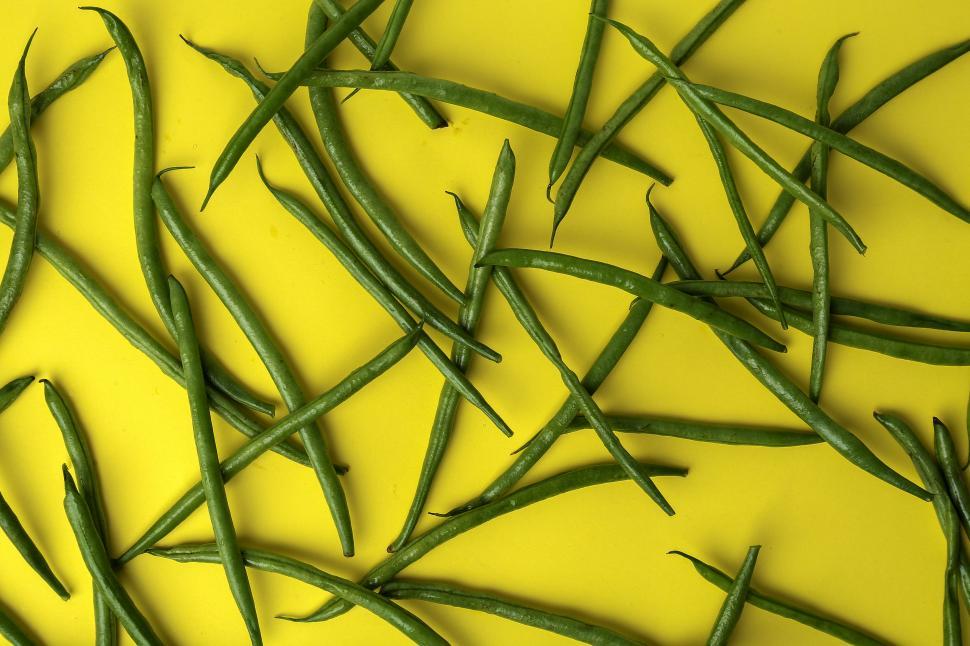 Free Image of Green beans randomly arranged covering yellow background 