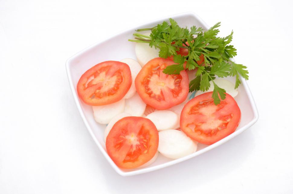 Free Image of the red tomato with radish sliced and green coriander in the plastic plate isolated on white background. 