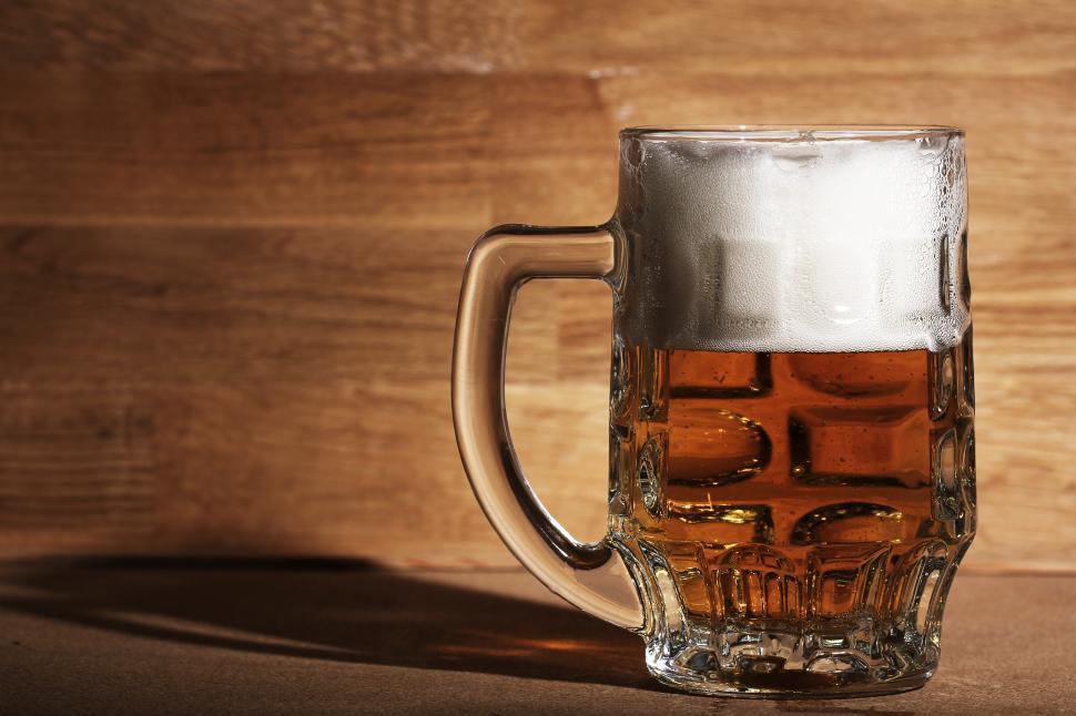 Free Image of Glass of beer with foamy head over wooden surface 