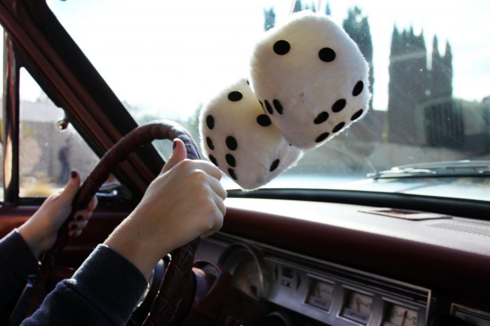 Free Image of Inside of car with woman hands on wheel with fluffy dices 