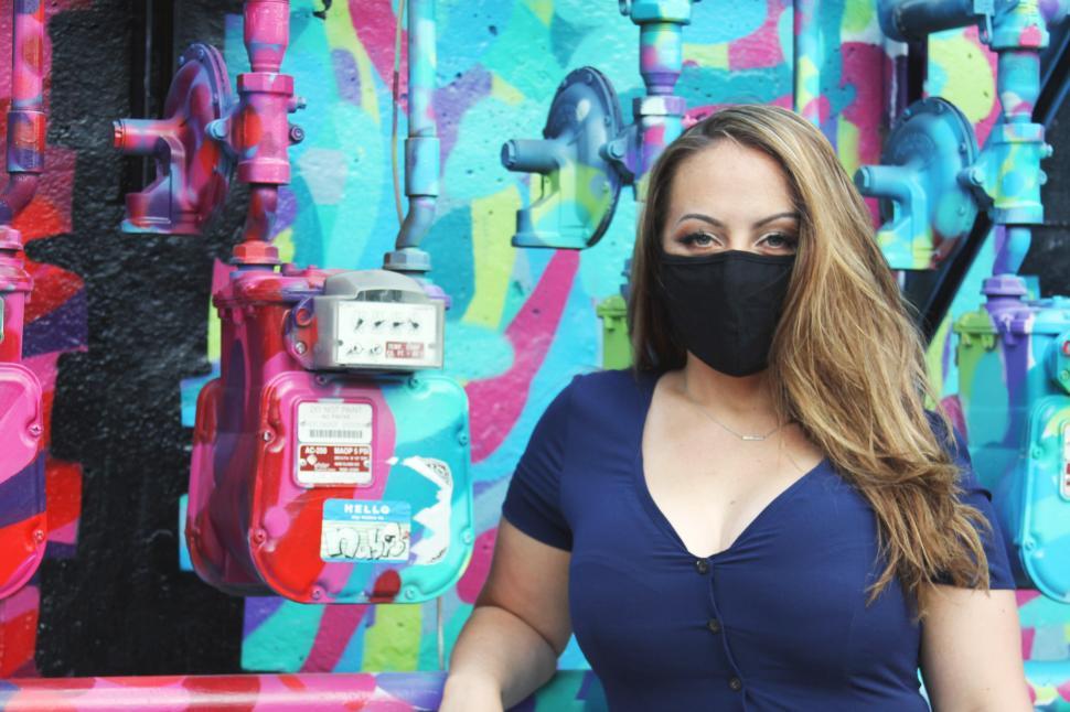 Free Image of Woman in face mask with graffiti wall 
