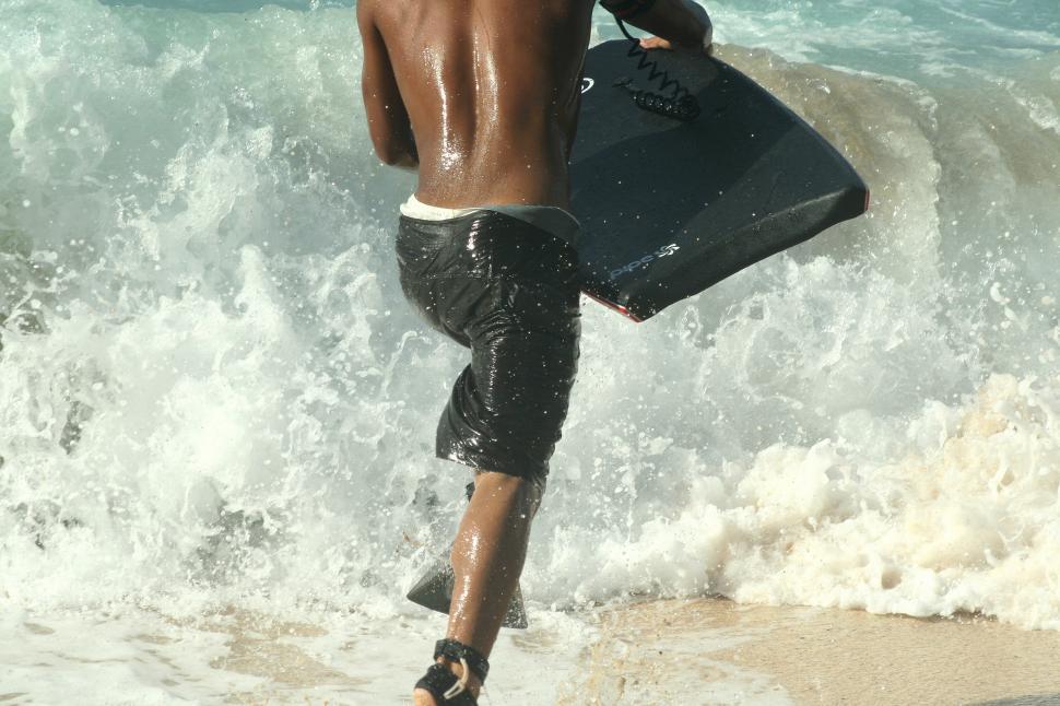 Free Image of Backside view of man with surfboard and ocean - surfer run 