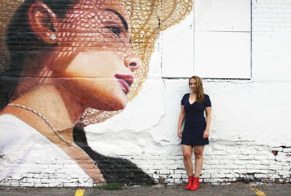 Free Image of Female fashion model posing with woman in hat painting on wall 