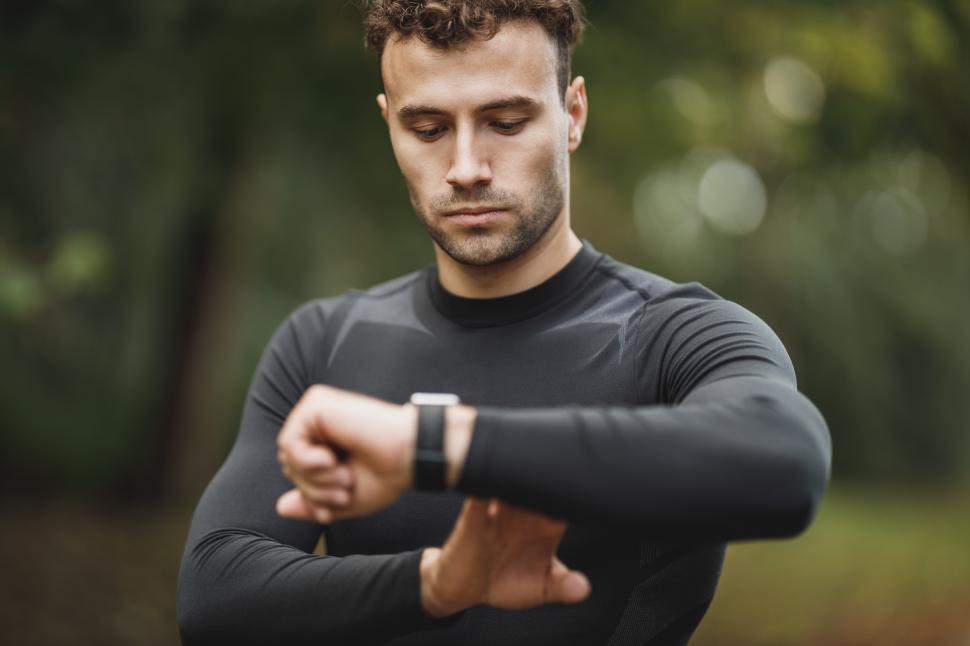 Free Image of Male athlete looking at his wristwatch after running in the park 