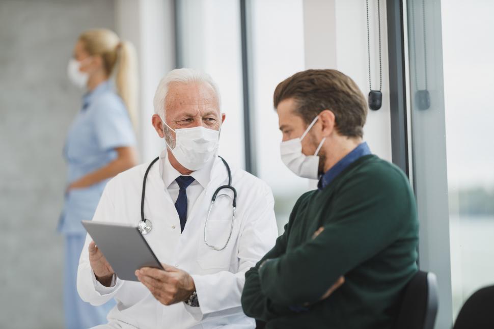Free Image of Young man consulting with senior male doctor in hospital with fa 