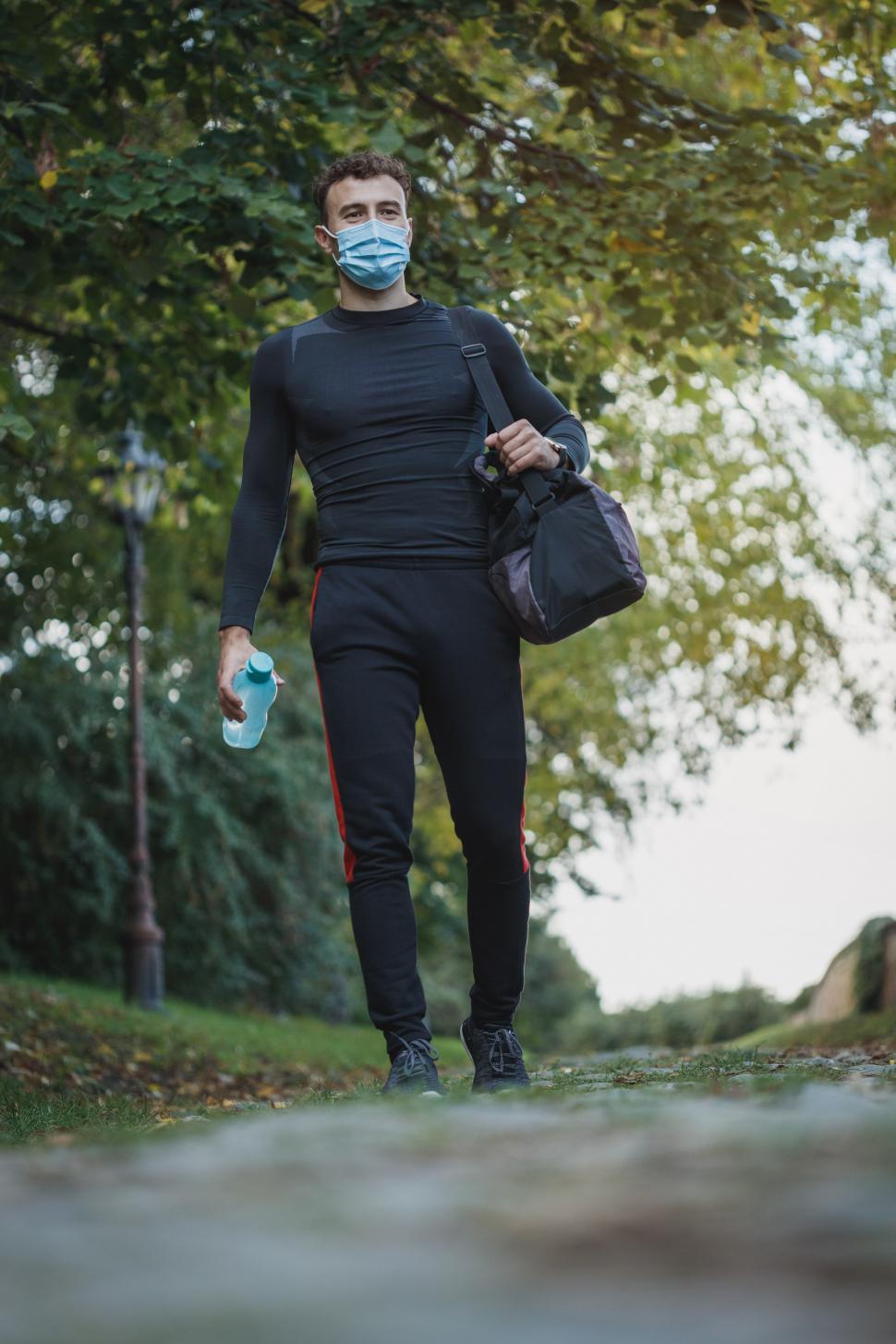 Free Image of Male athlete with bag and Coronavirus face mask in the park 