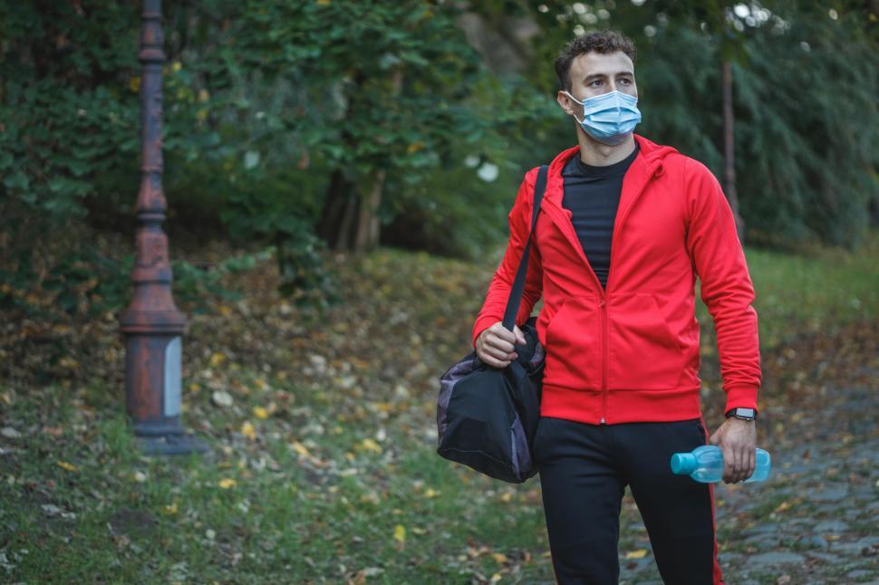 Free Image of Male athlete with surgical mask and gym bag, walking in the park 