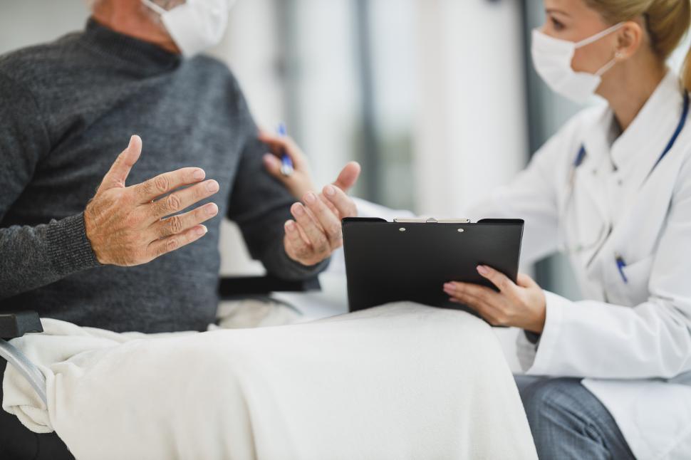 Free Image of Female caregiver with face mask, talking to old-aged person in w 