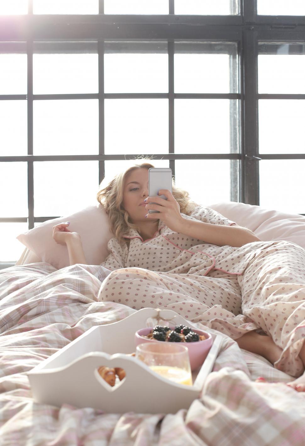Free Image of Woman in bed with her phone and breakfast 