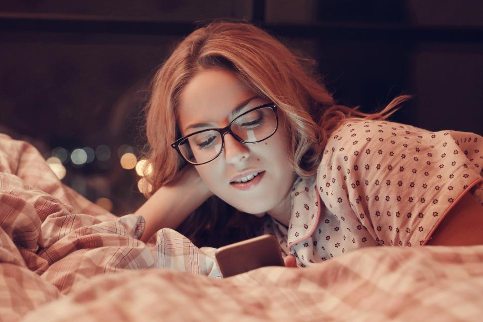 Free Image of Girl in bed, reading from her phone 