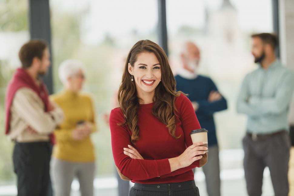 Free Image of Female manager with confident smile holding coffee cup in office 
