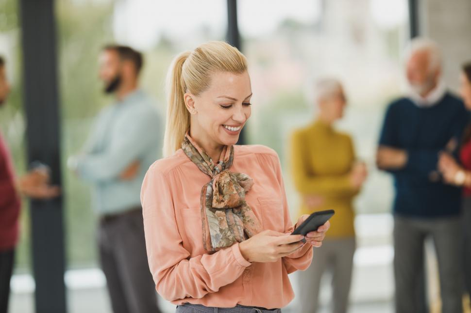 Free Image of Happy female office worker checking messages on her smartphone 