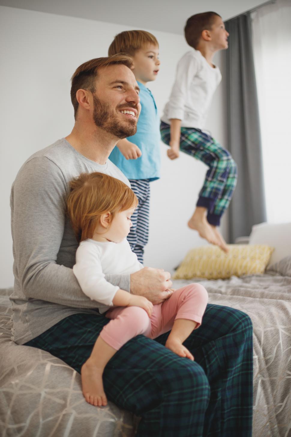 Free Image of Happy Caucasian father with his kids on bed 