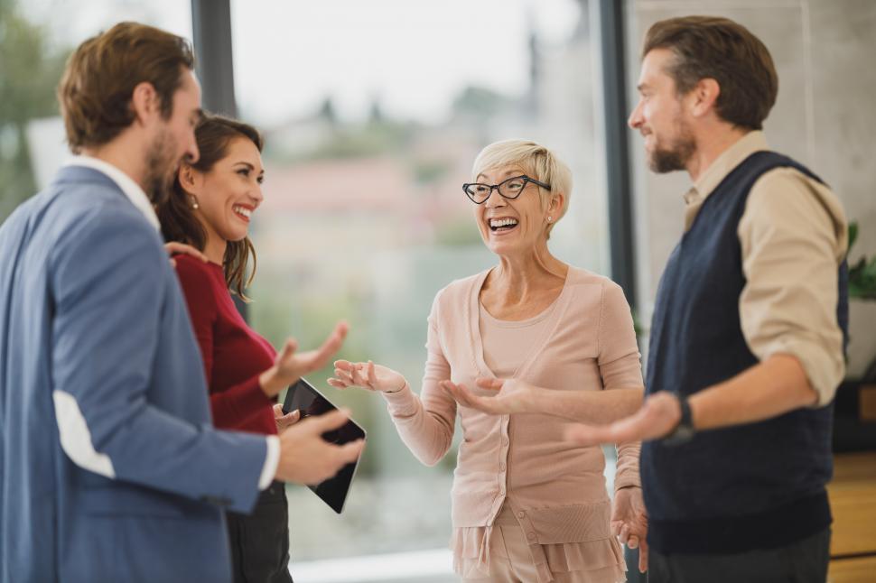Free Image of Coworkers talking and smiling while standing in the office 
