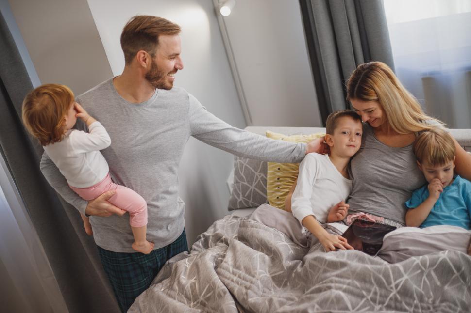 Free Image of Young happy mother hugging and sitting with her children on bed 
