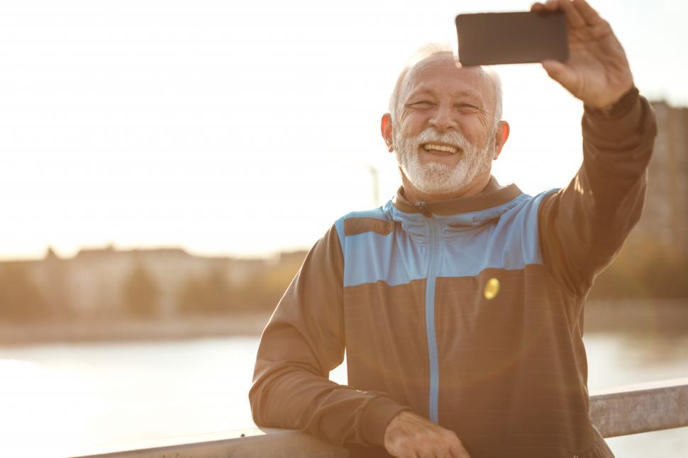 Free Image of Happy older man taking a selfie on the bridge 
