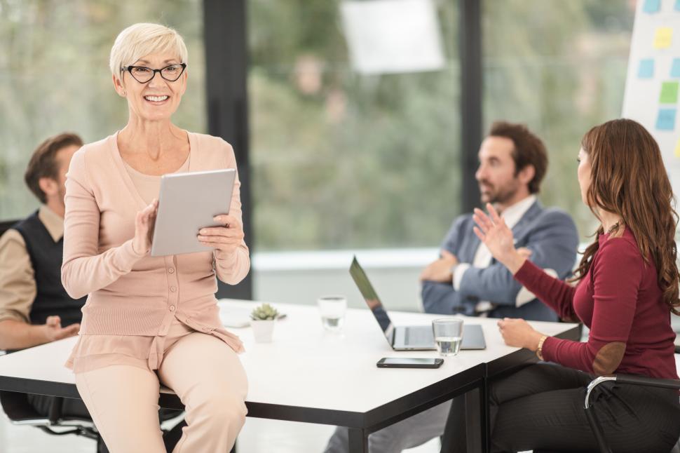 Free Image of Smiling senior female executive with tablet during meeting in office 