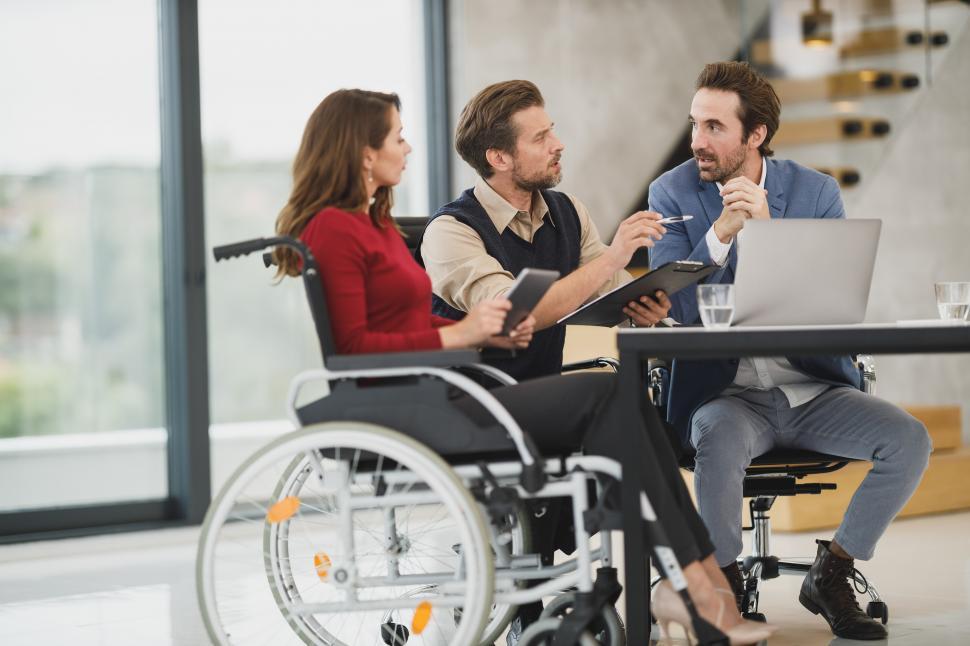 Free Image of Woman who uses a wheelchair with two male colleagues working in office environment 