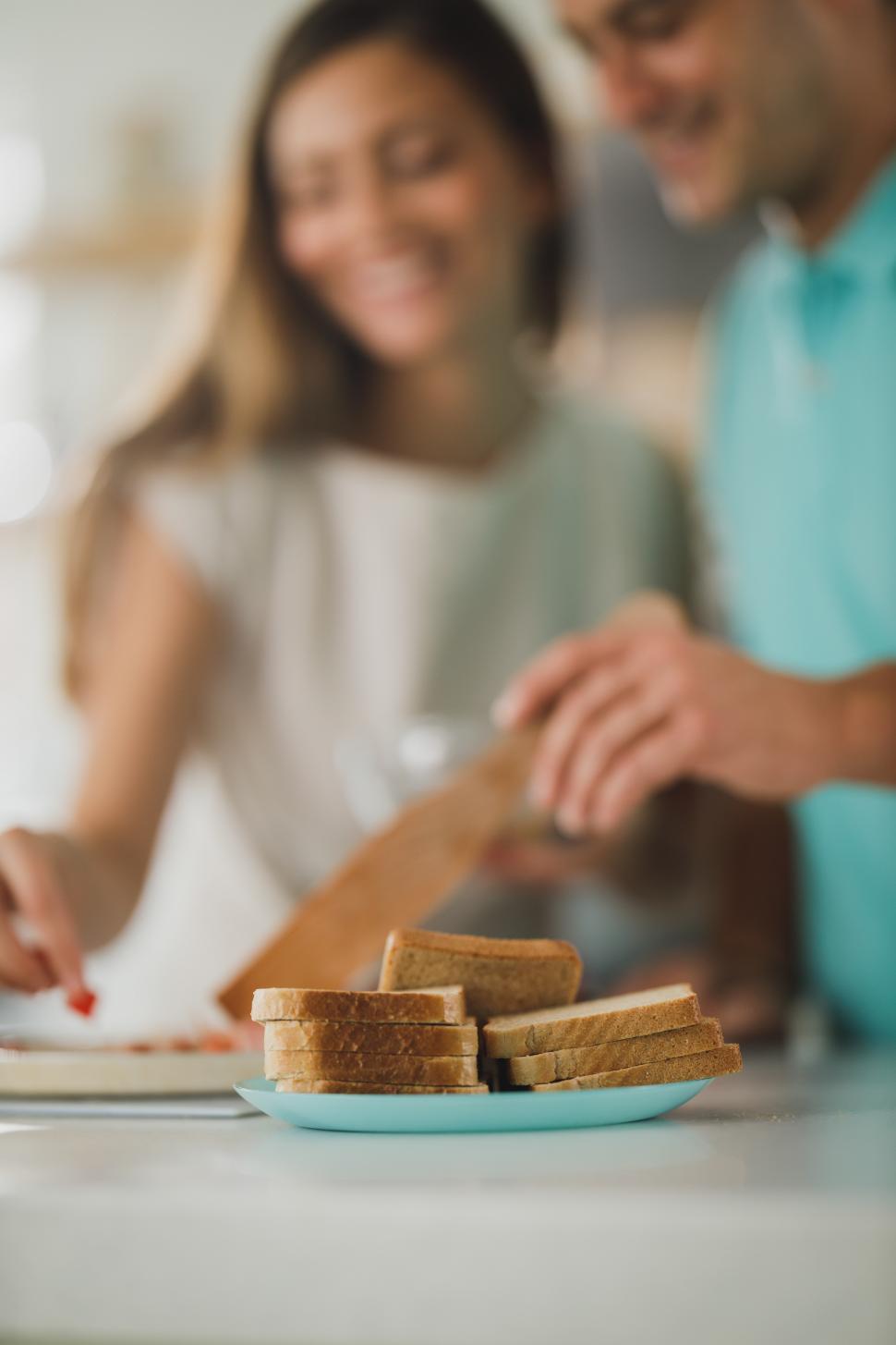 Free Image of Slices of toast bread and couple in kitchen 