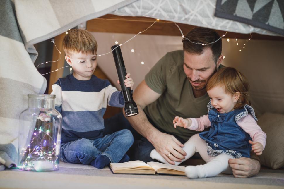Free Image of Happy family father and children reading a book with a flashligh 