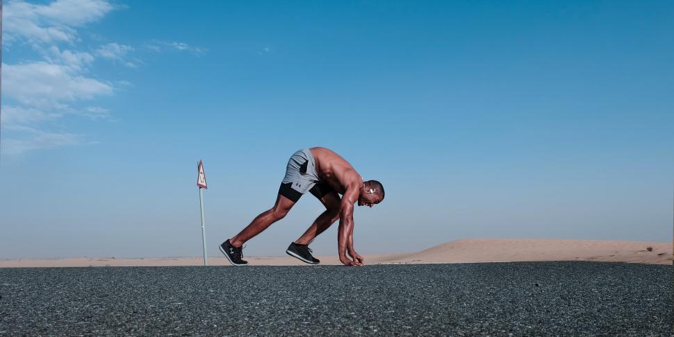Free Image of Muscular man ready to start running on desert road 