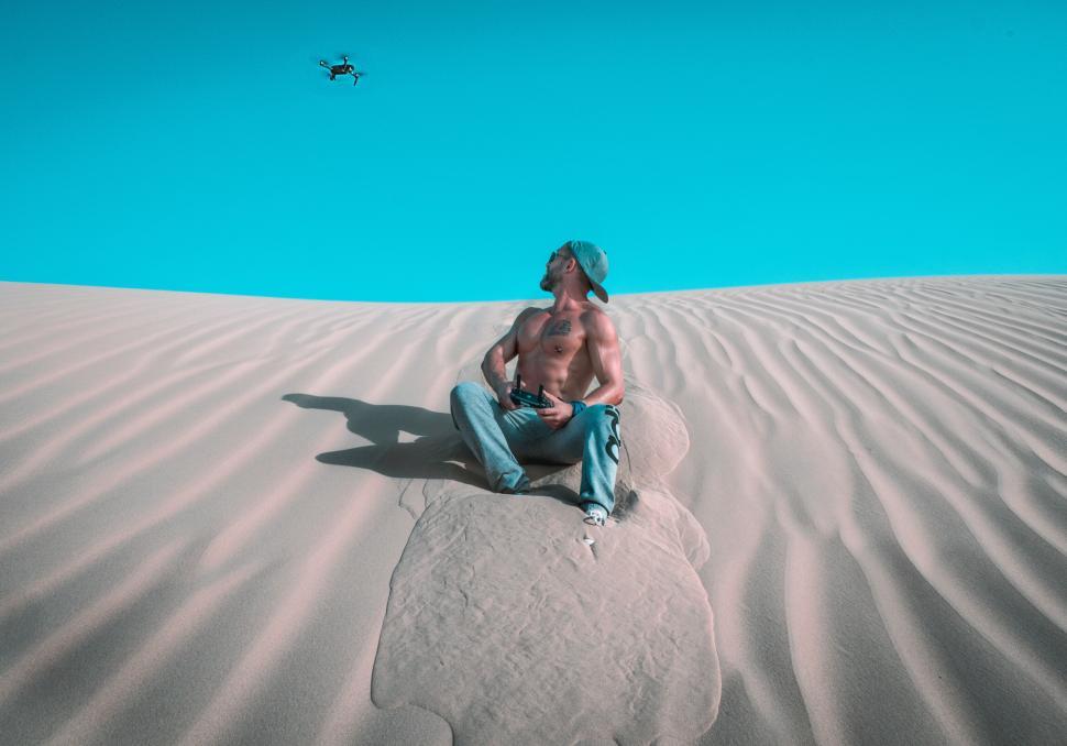 Free Image of Muscular man with drone camera in the sand dunes 