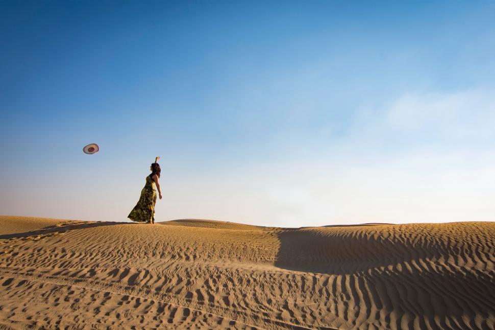 Free Image of Woman throws hat in the desert 