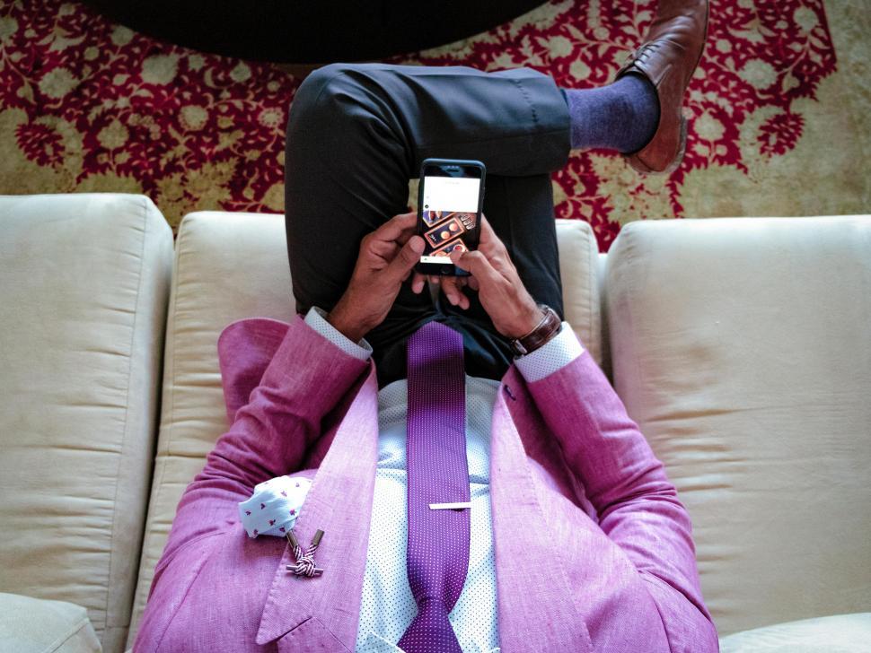 Free Image of Young man in formal clothing with mobile phone sitting on the so 