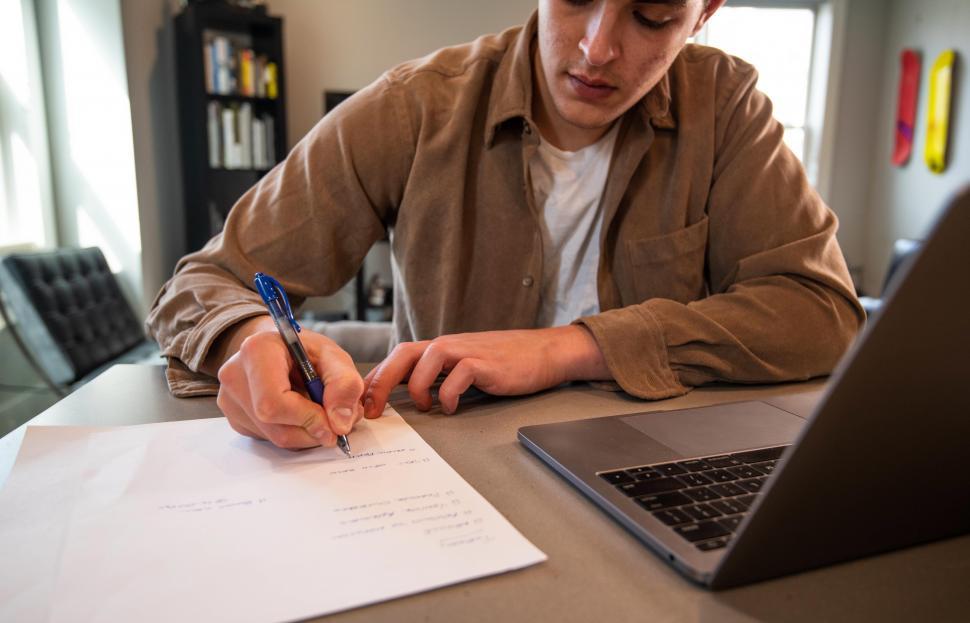Free Image of Businessman or student writing on paper at desk in office 