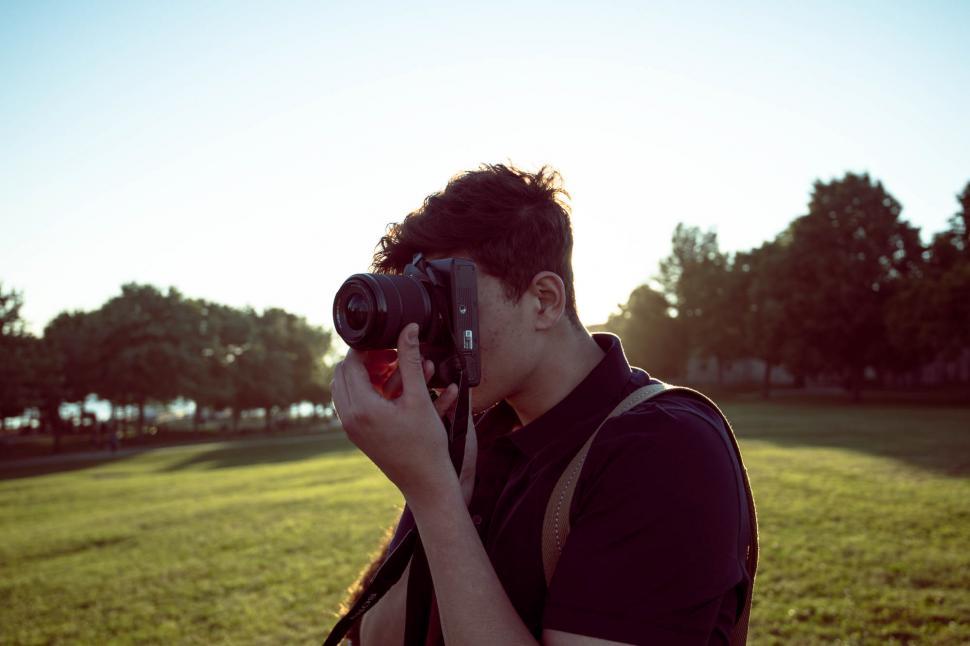 Free Image of Young man with camera in the green grass park 