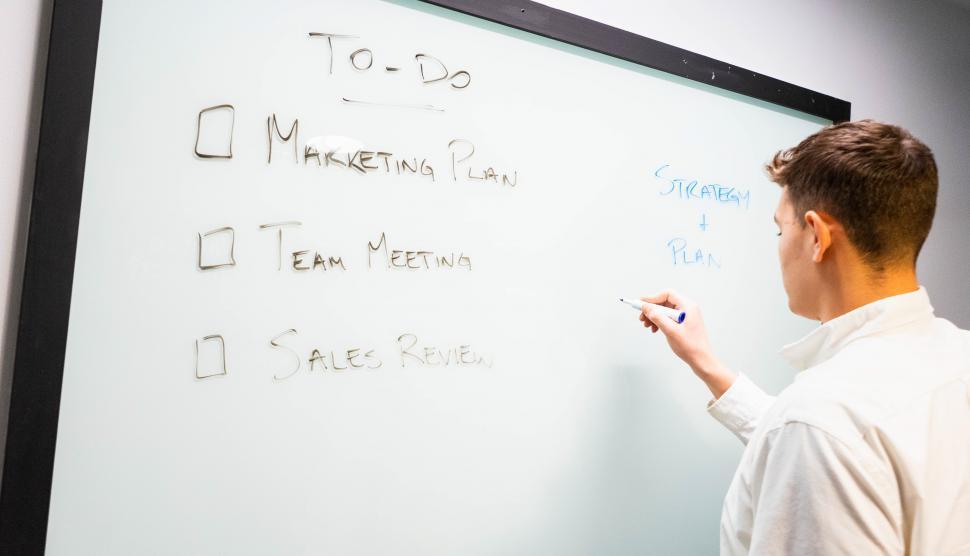 Free Image of Young man writing plan and schedule on whiteboard 