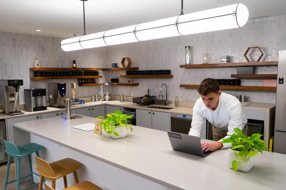 Free Image of Young man working on laptop in kitchen area 