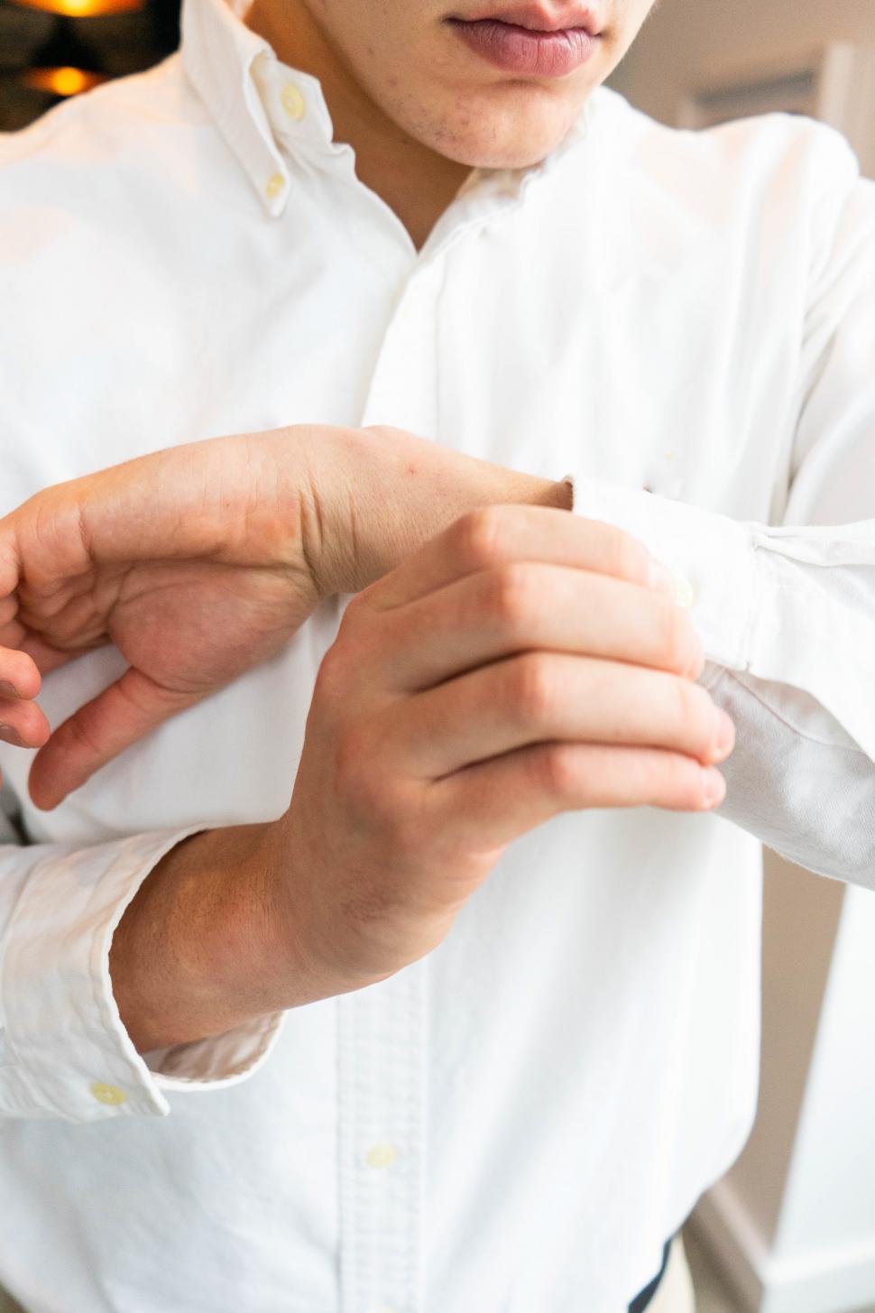 Free Image of Young man hands fastening buttons on shirt sleeve 