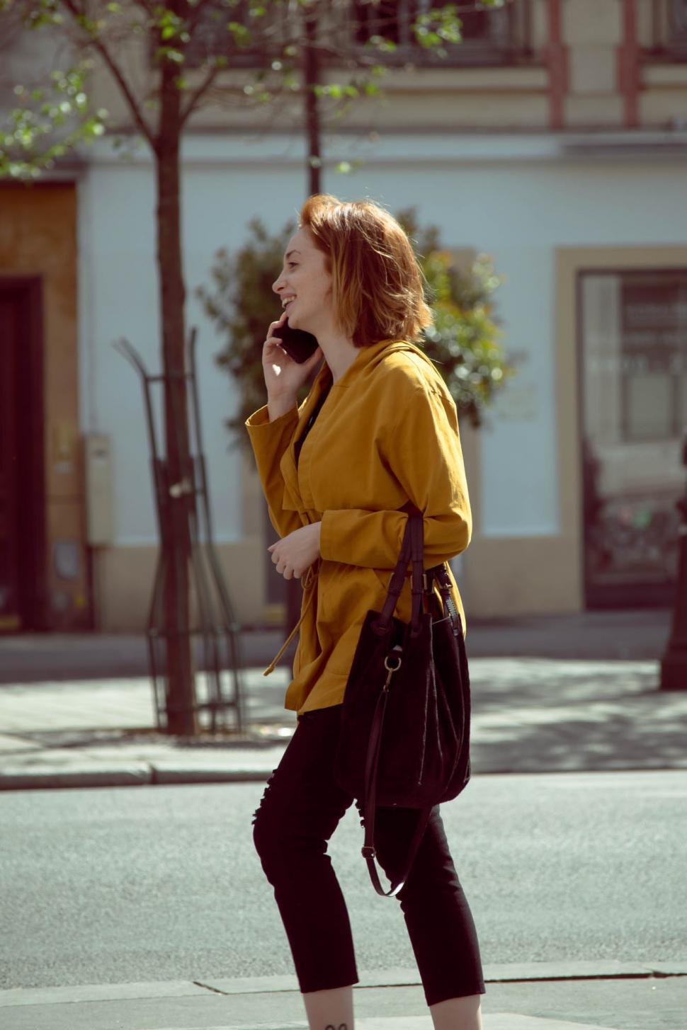 Free Image of Smiling woman talking on mobile phone on the street 