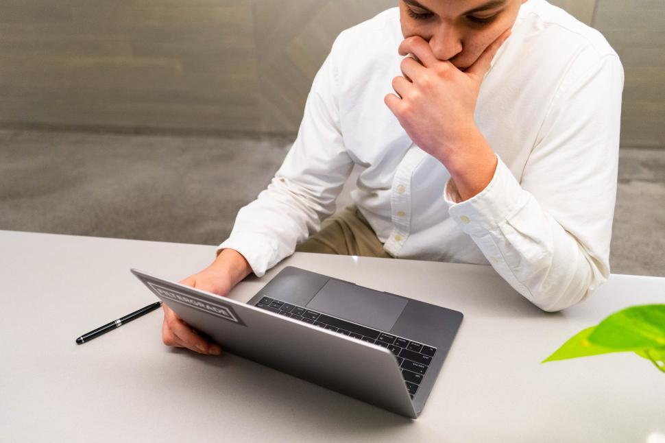 Free Image of Young man sitting and thinking in front of laptop 