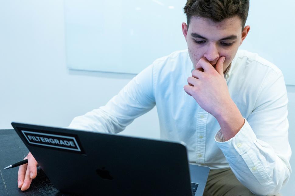 Free Image of Young man sitting and thinking in front of laptop 