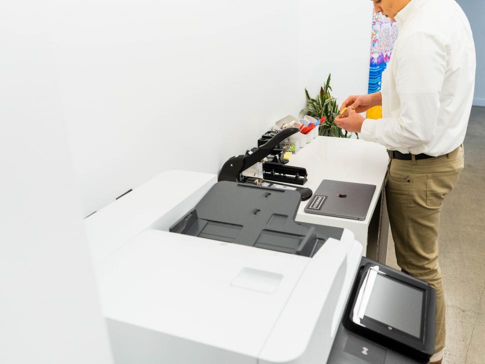 Free Image of Young man and photocopier machine with laptop on table 