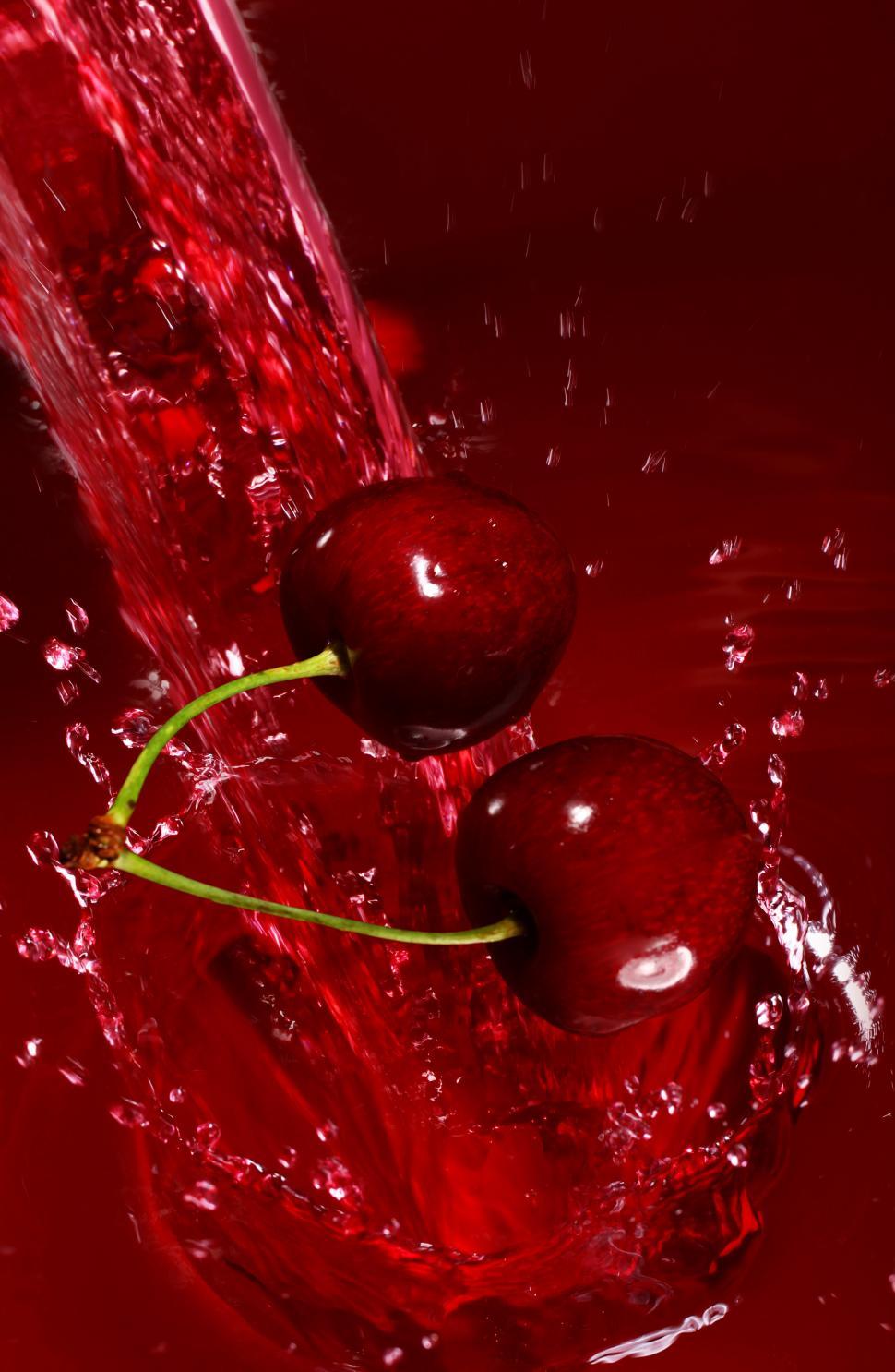 Free Image of Two cherries fall into stream of juice 