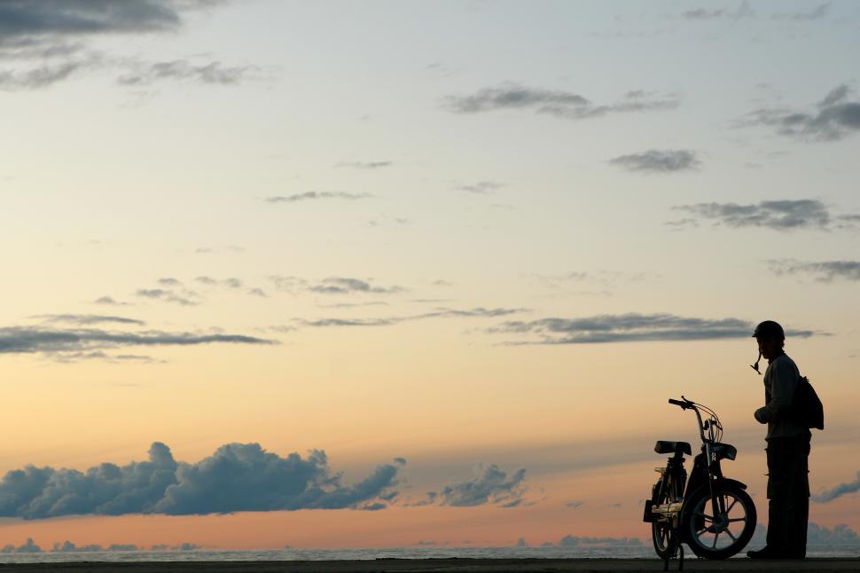Free Image of yellow sunset with person and a scooter silhouette 