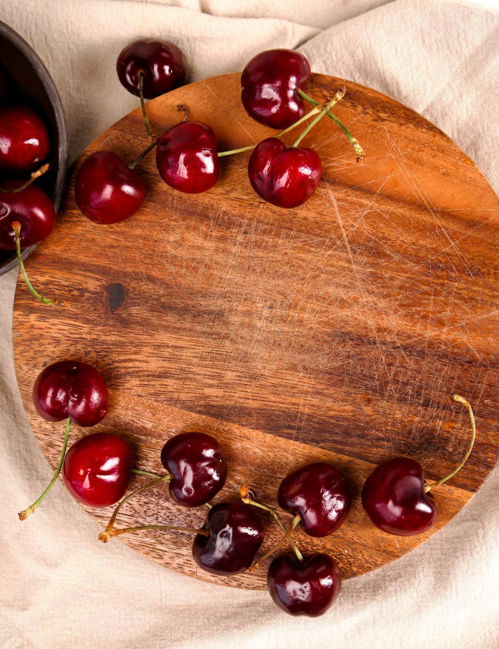 Free Image of Cherries on a wooden cutting board with middle copyspace 