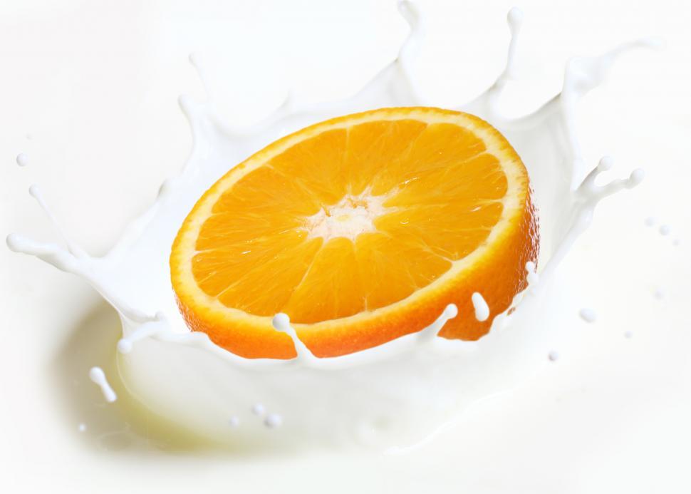 Free Image of Orange half falls into splash of milk 