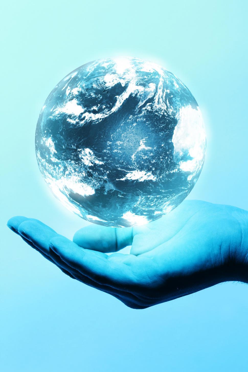 Free Image of Glowing earth sphere hovering over open hand 