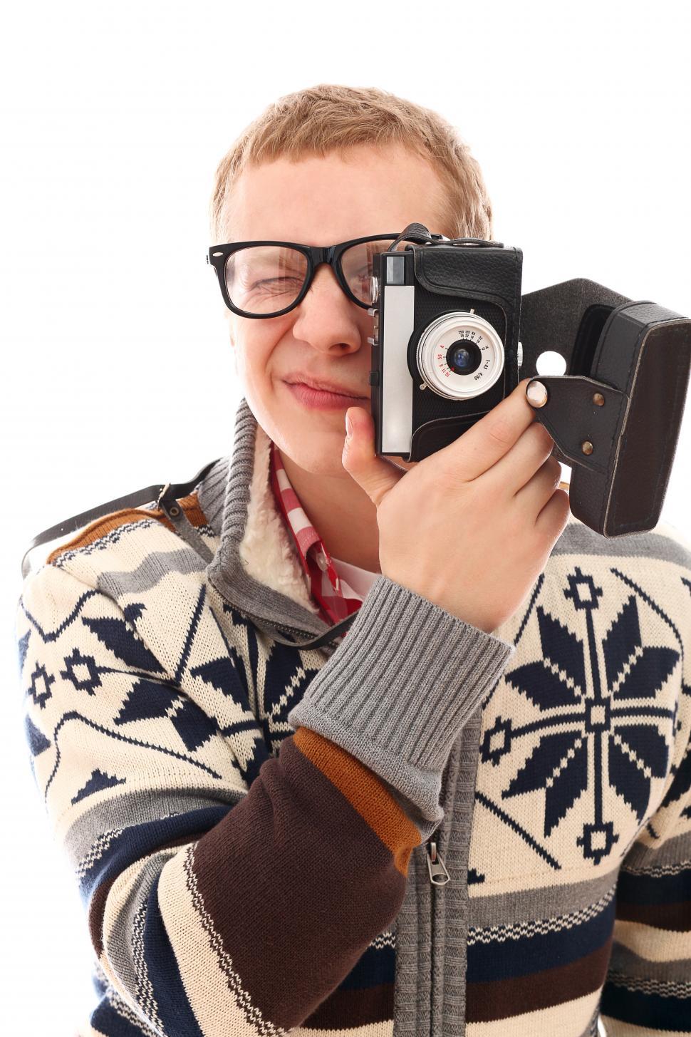 Free Image of Young man in a sweater holding up a vintage camera 