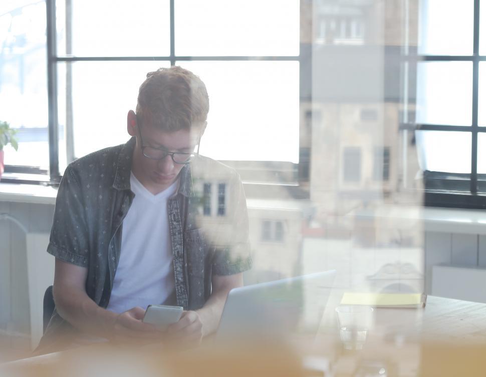 Free Image of Guy in the office seen though layers of glass 