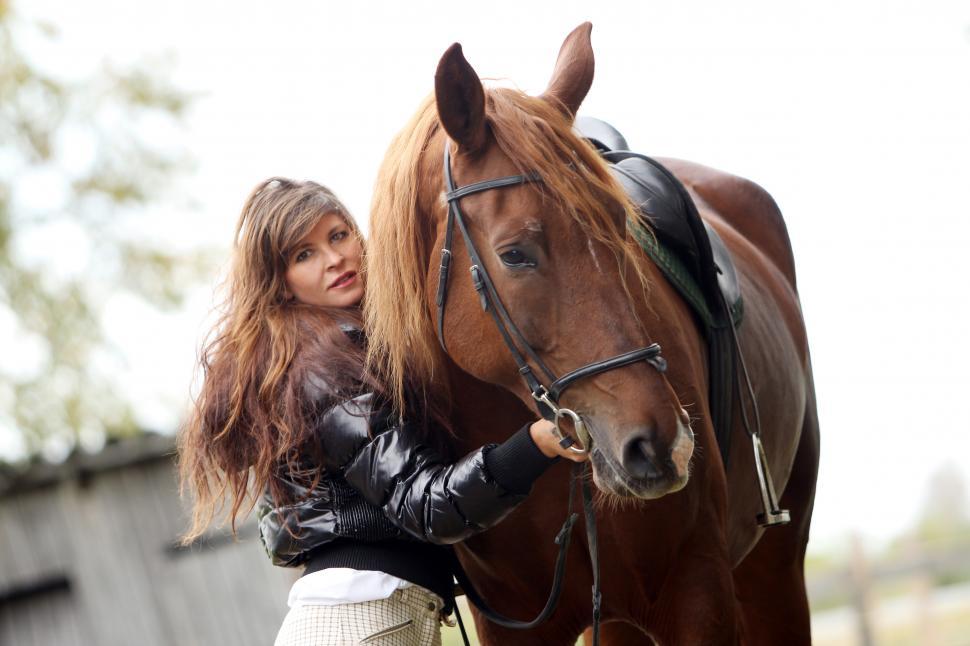 Free Image of Woman with her brown horse, looking at the camera 