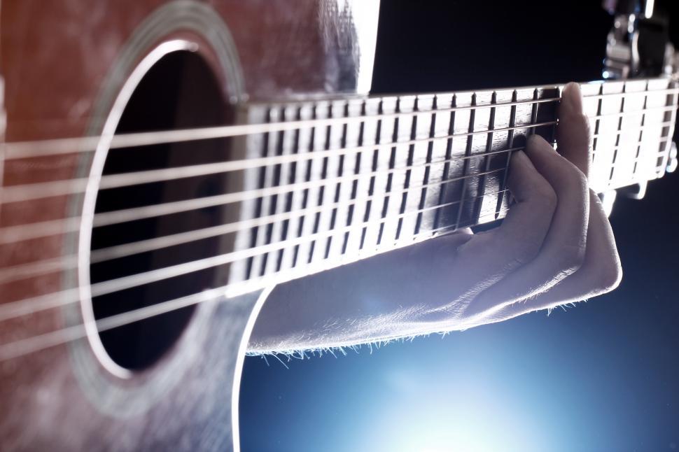 Free Image of Musician playing on guitar under stage lights 
